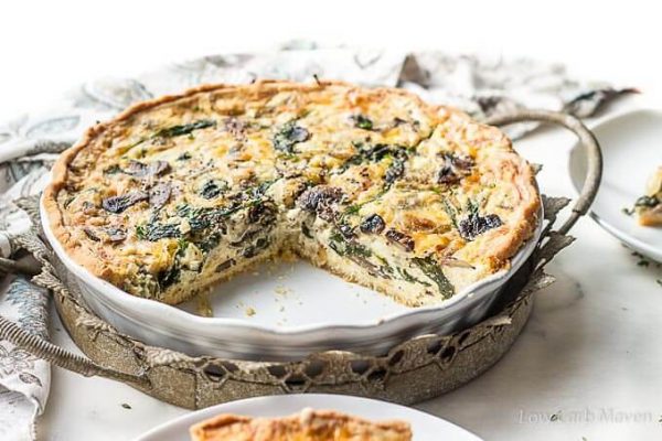 Spinach and mushroom quiche in a white quiche dish.