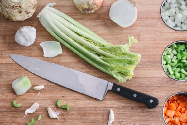 Vegetables for chicken soup on a cutting board with chefs knife.
