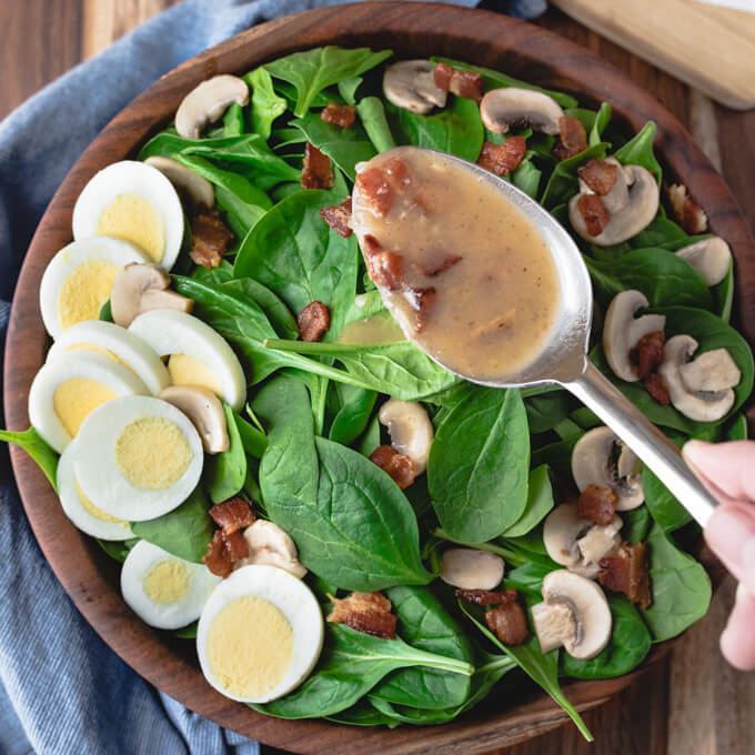 Spinach salad with warm bacon dressing with hardboiled eggs and mushrooms.
