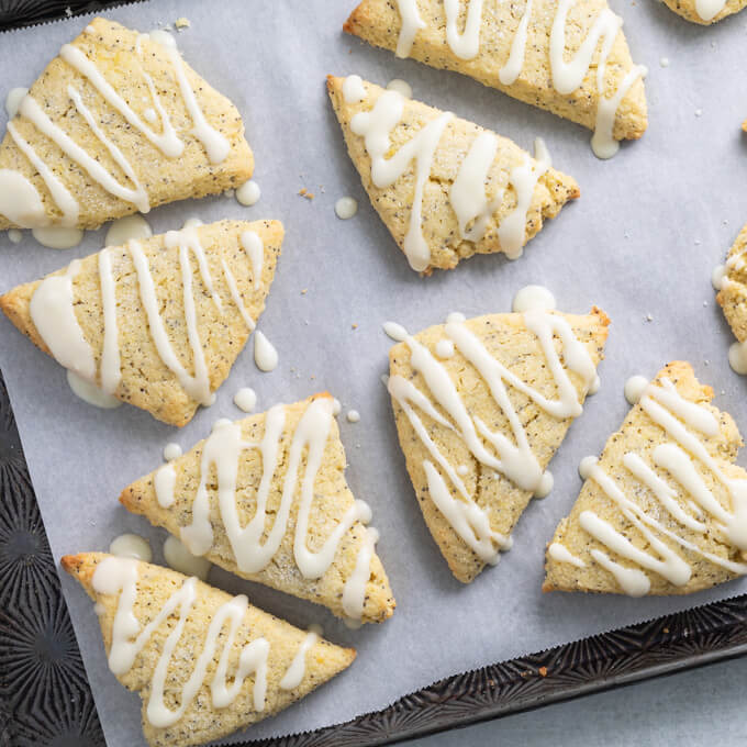 Low Carb Lemon Poppy Seed Scones with lemon glaze on parchment lined sheet pan