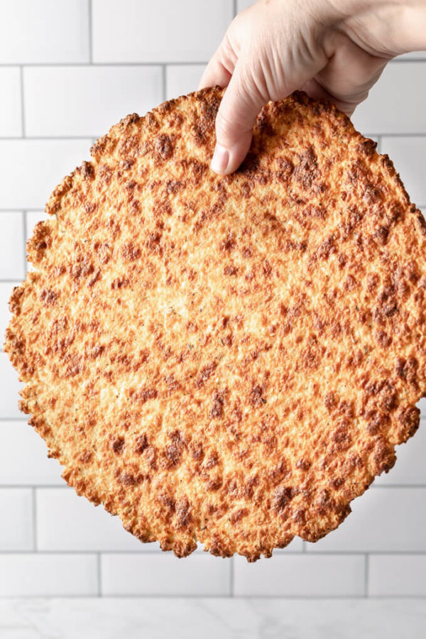 crispy keto cauliflower pizza crust held in one hand