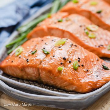 Keto salmon teriyaki filet topped with sesame seeds and sliced scallions on gray platter.